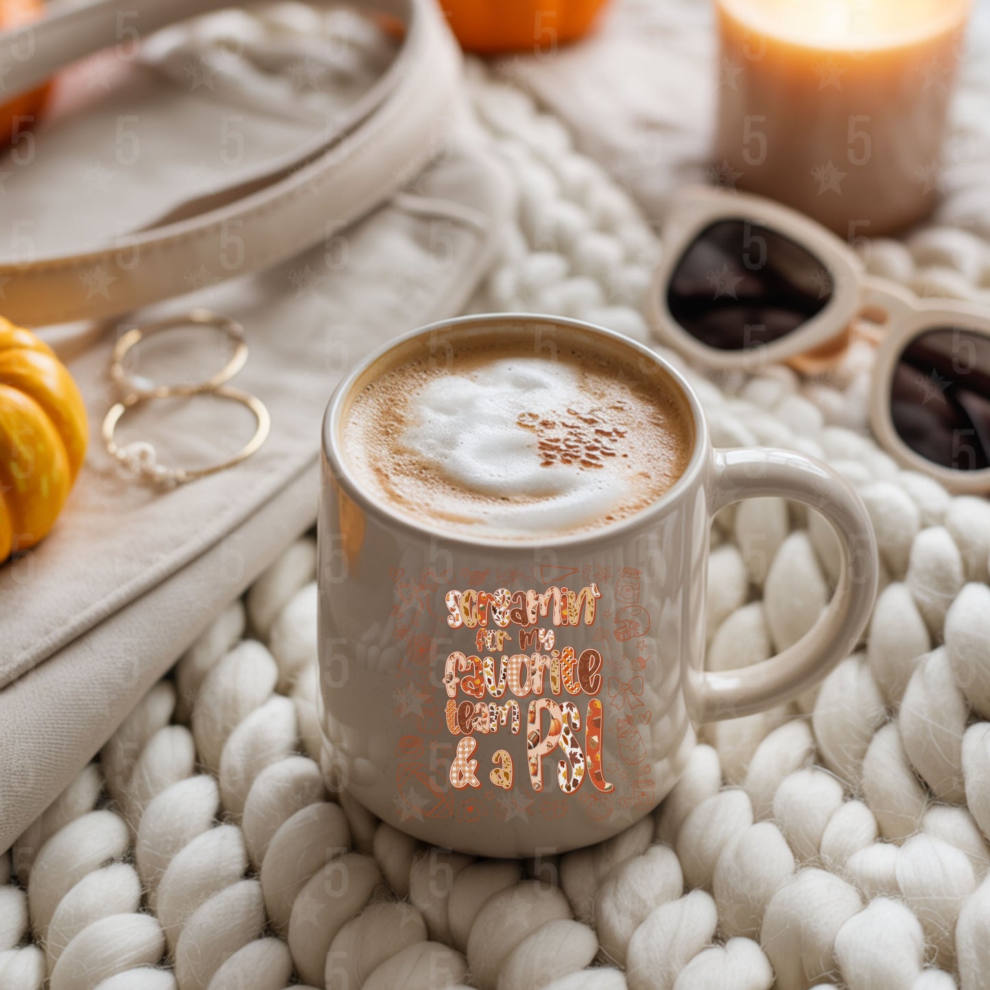 Cup of coffee with decorative text on a textured surface with pumpkins and candles.