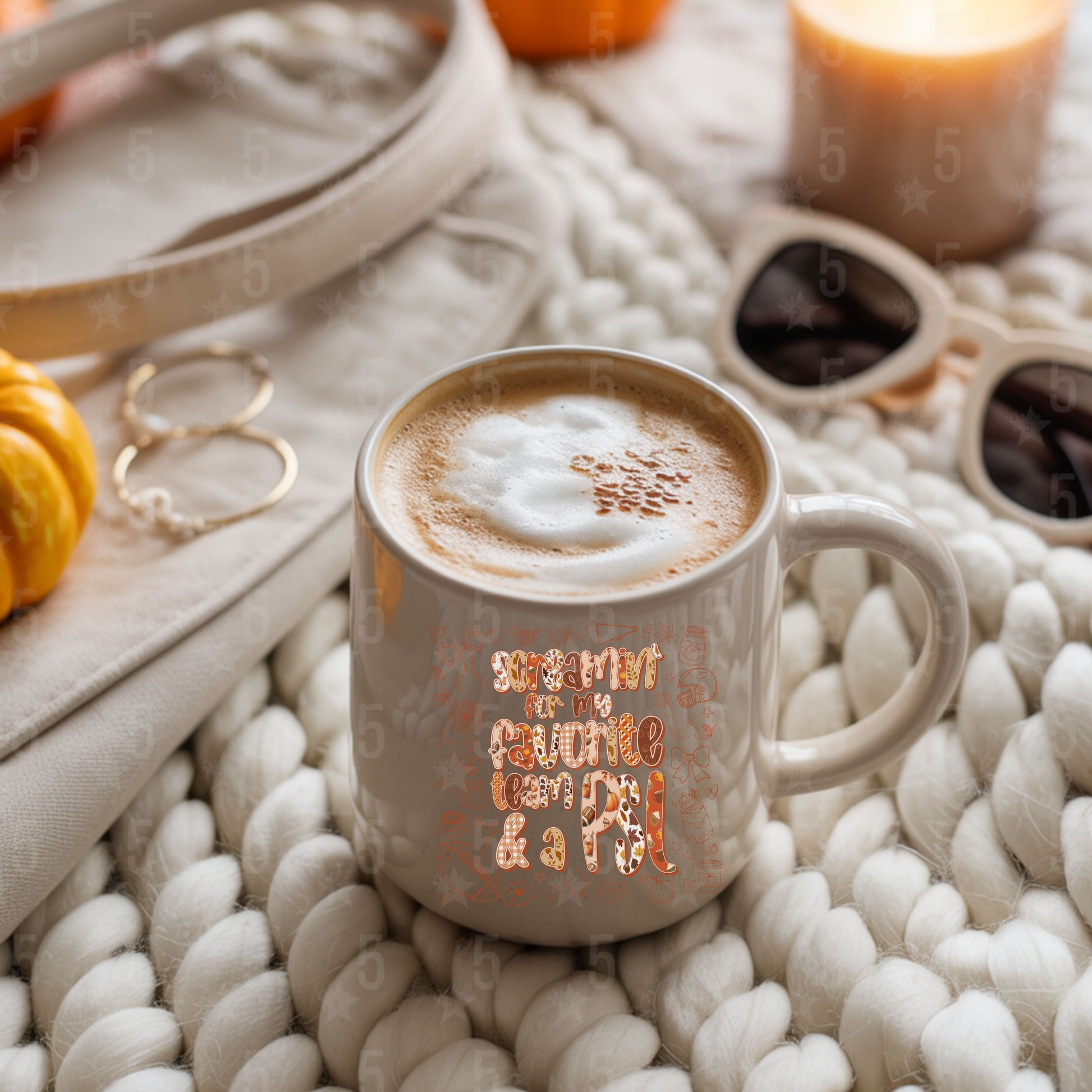 Cup of coffee with decorative text on a textured surface with pumpkins and candles.
