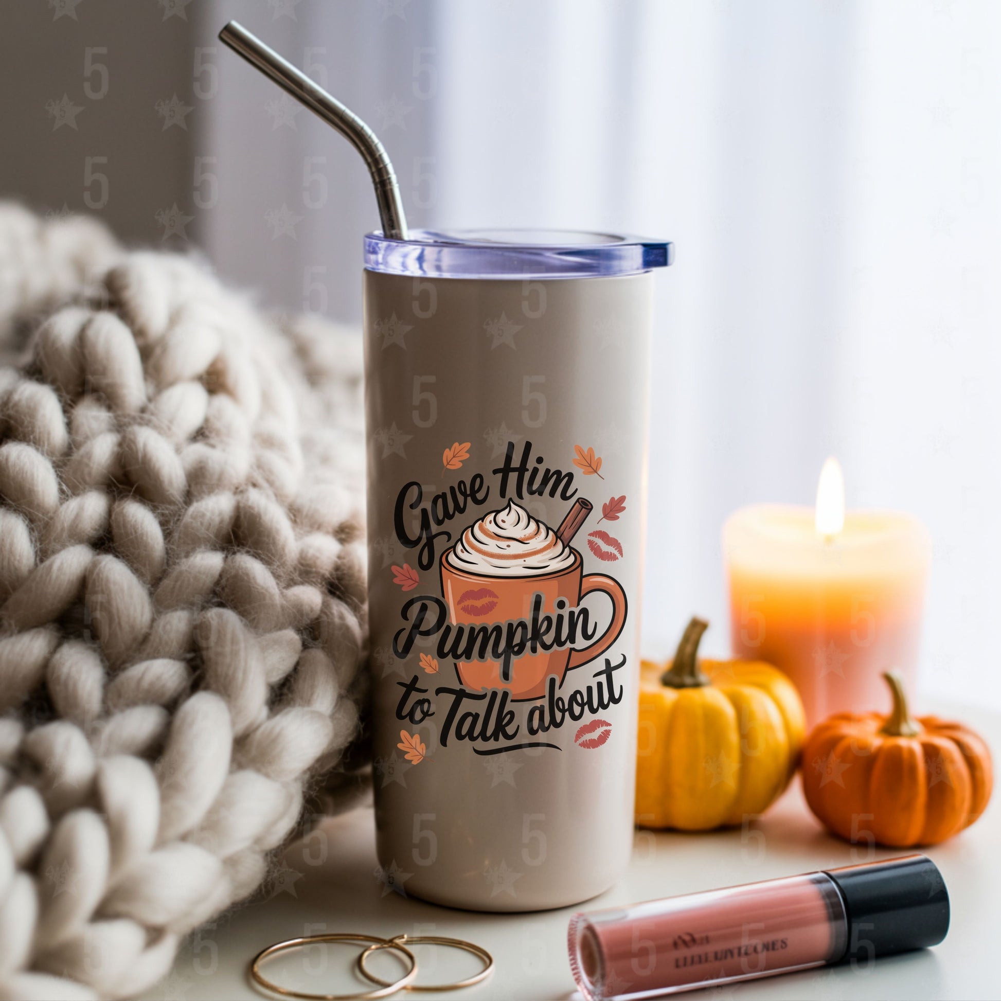 Tumbler with pumpkin spice design, candles, and pumpkins on a table.