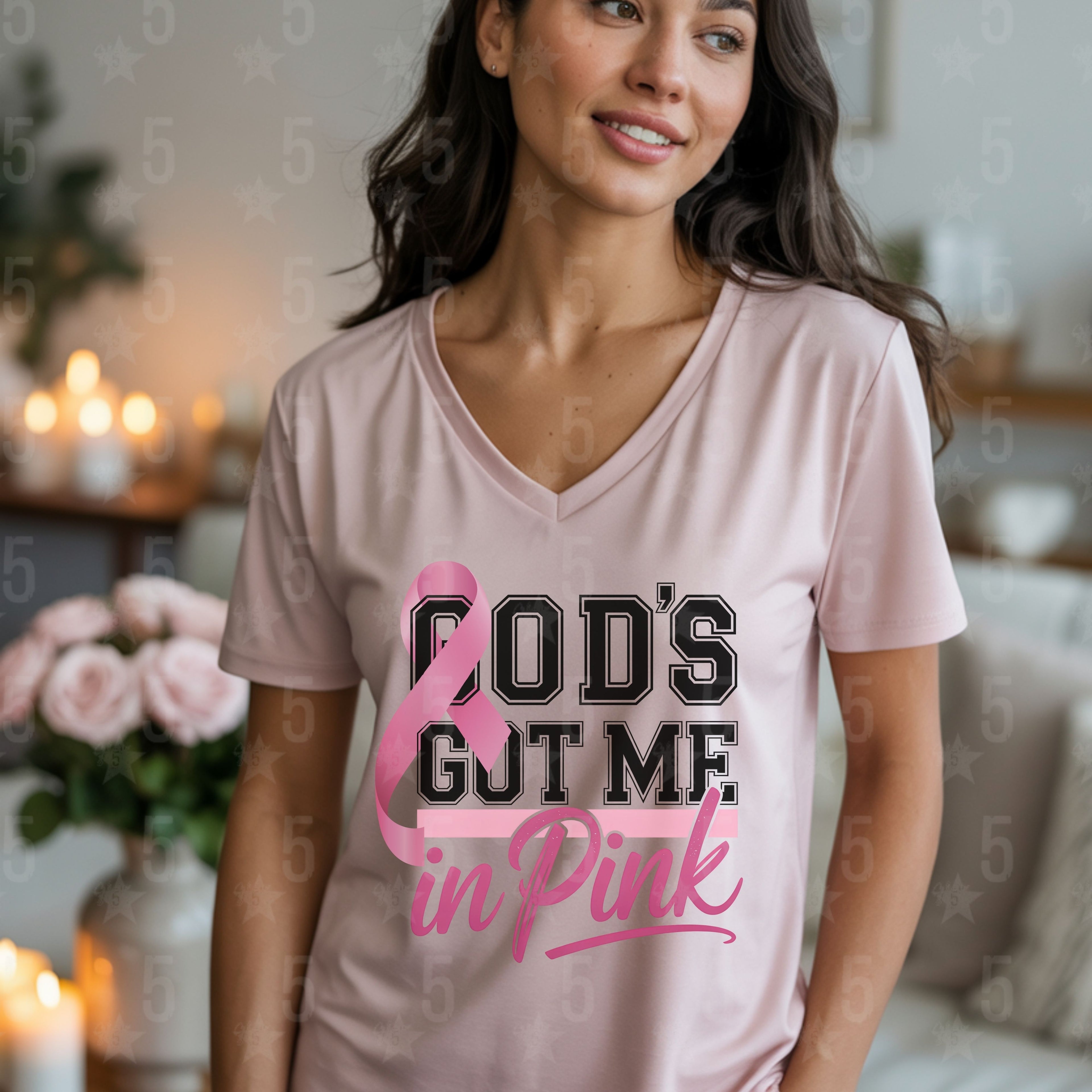 Woman wearing a pink t-shirt with 'God's got me in pink' text in a home setting.