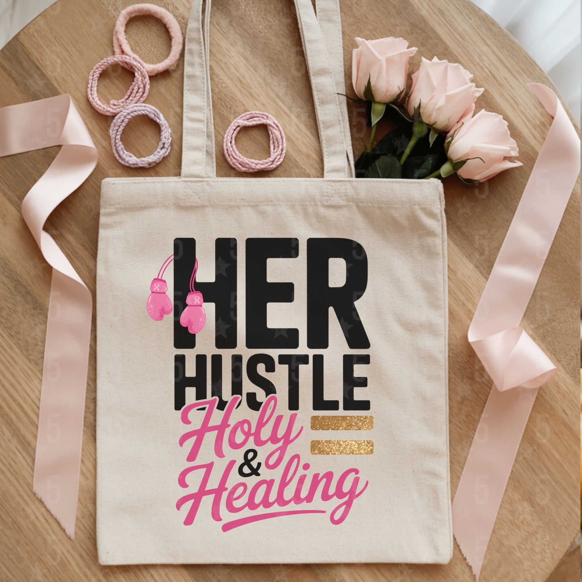 Tote bag with 'HER HUSTLE Holy & Healing' text on a wooden surface with ribbons and flowers.