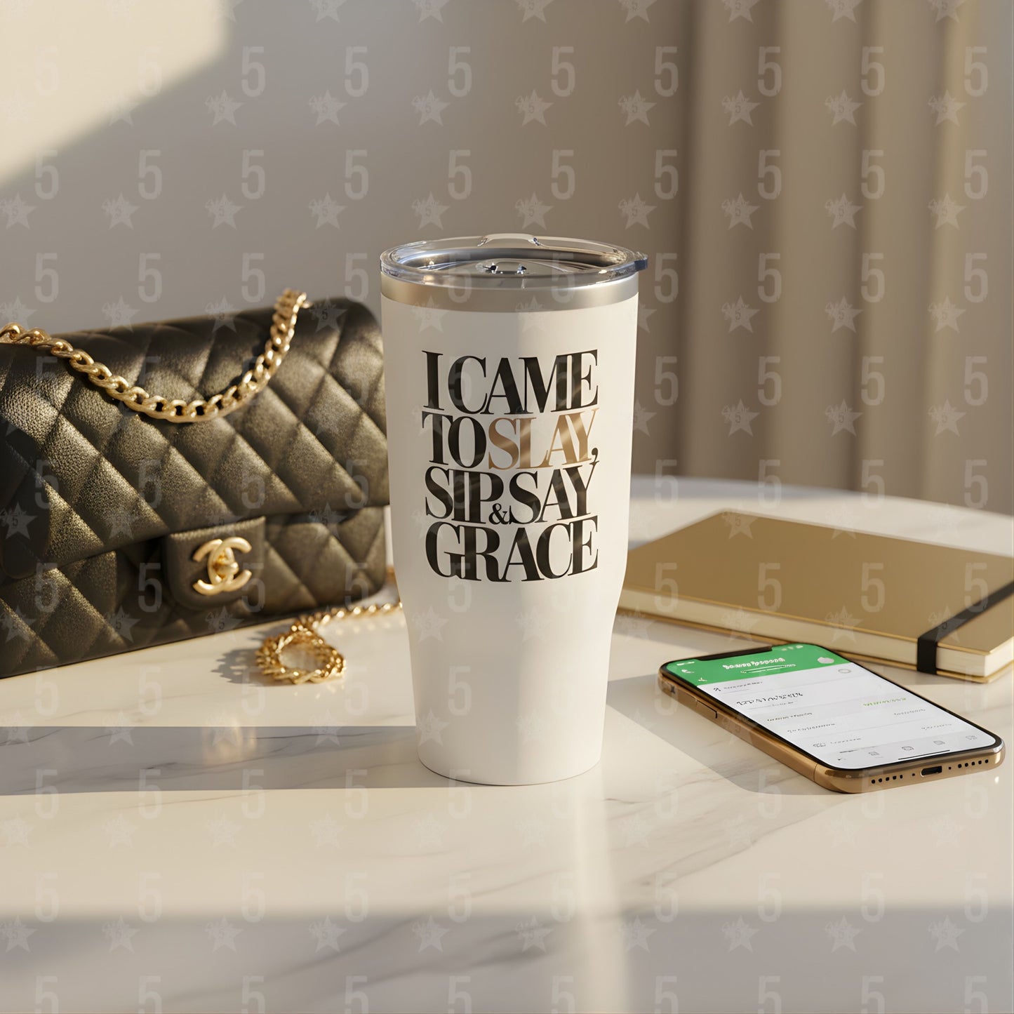 White tumbler with text on a surface with a handbag and phone in the background