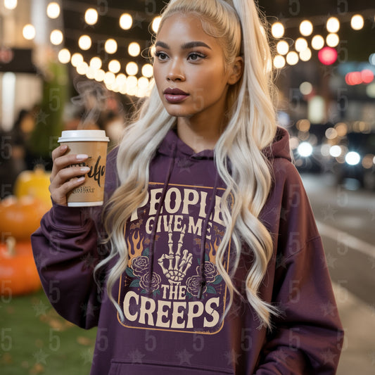 Woman wearing a purple hoodie with a unique design, holding a coffee cup on a street.