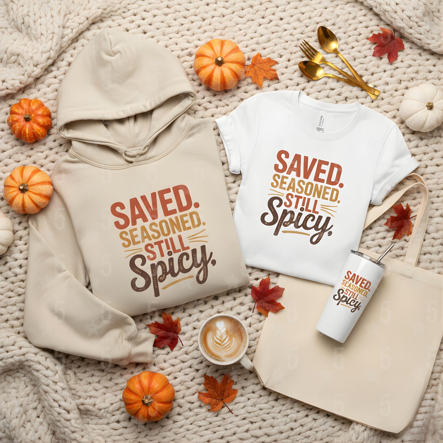 Hoodie, t-shirt, mug, and tote bag with 'Saved. Seasoned. Still Spicy.' text on a textured surface with pumpkins and leaves.