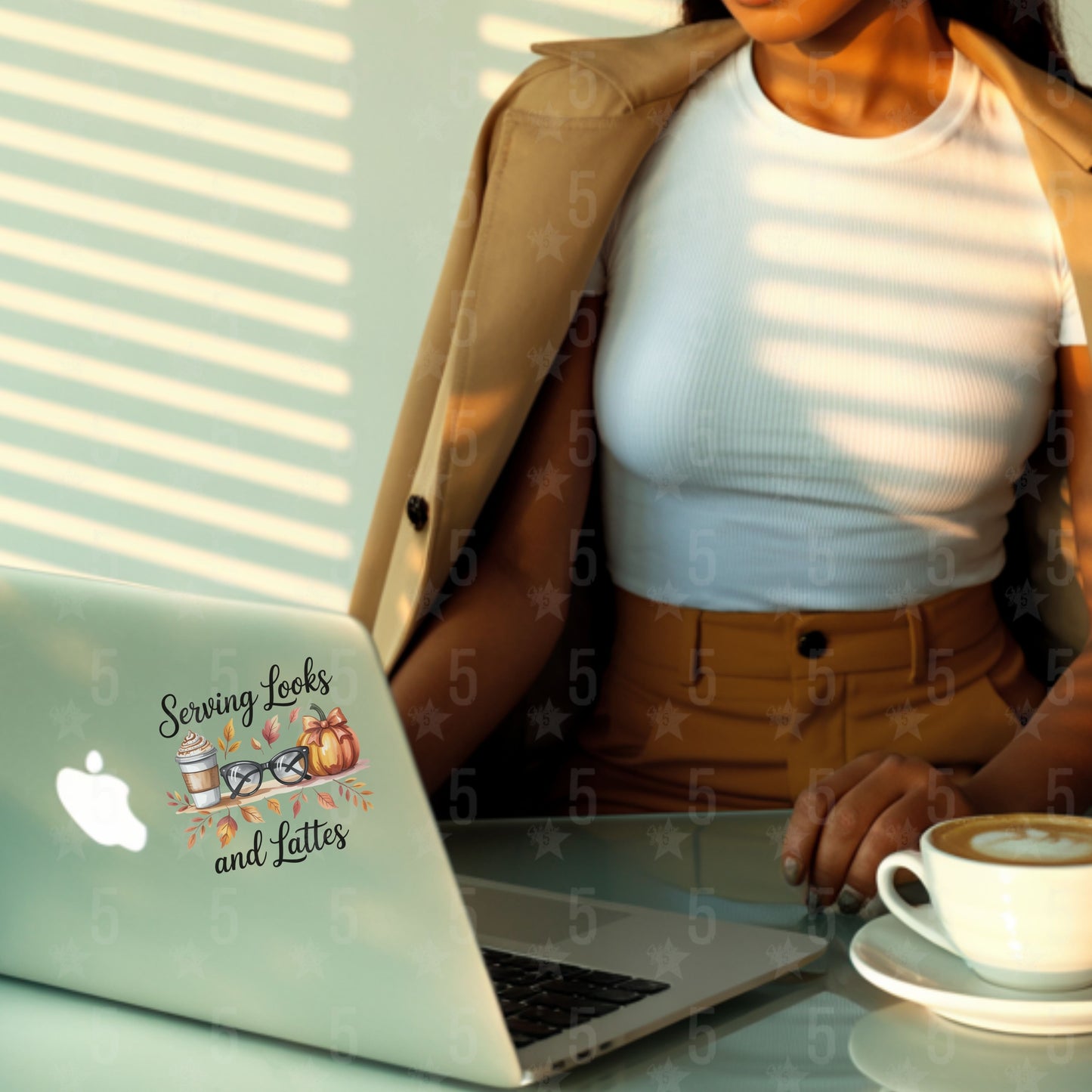 Person using a laptop with a 'Serving Lattes and Lattes' sticker, next to a cup of coffee.