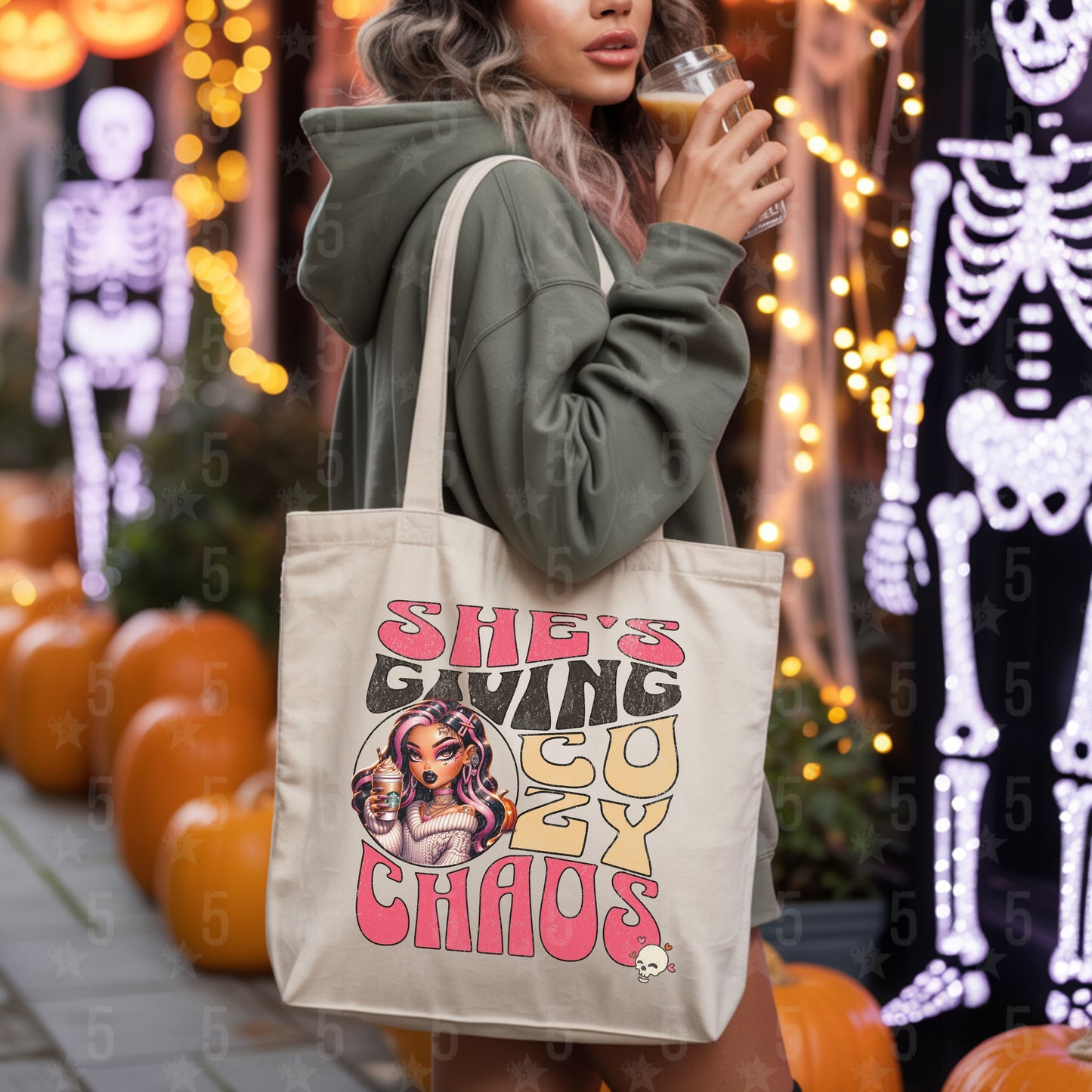 Person holding a tote bag with a graphic design and text, surrounded by Halloween decorations.