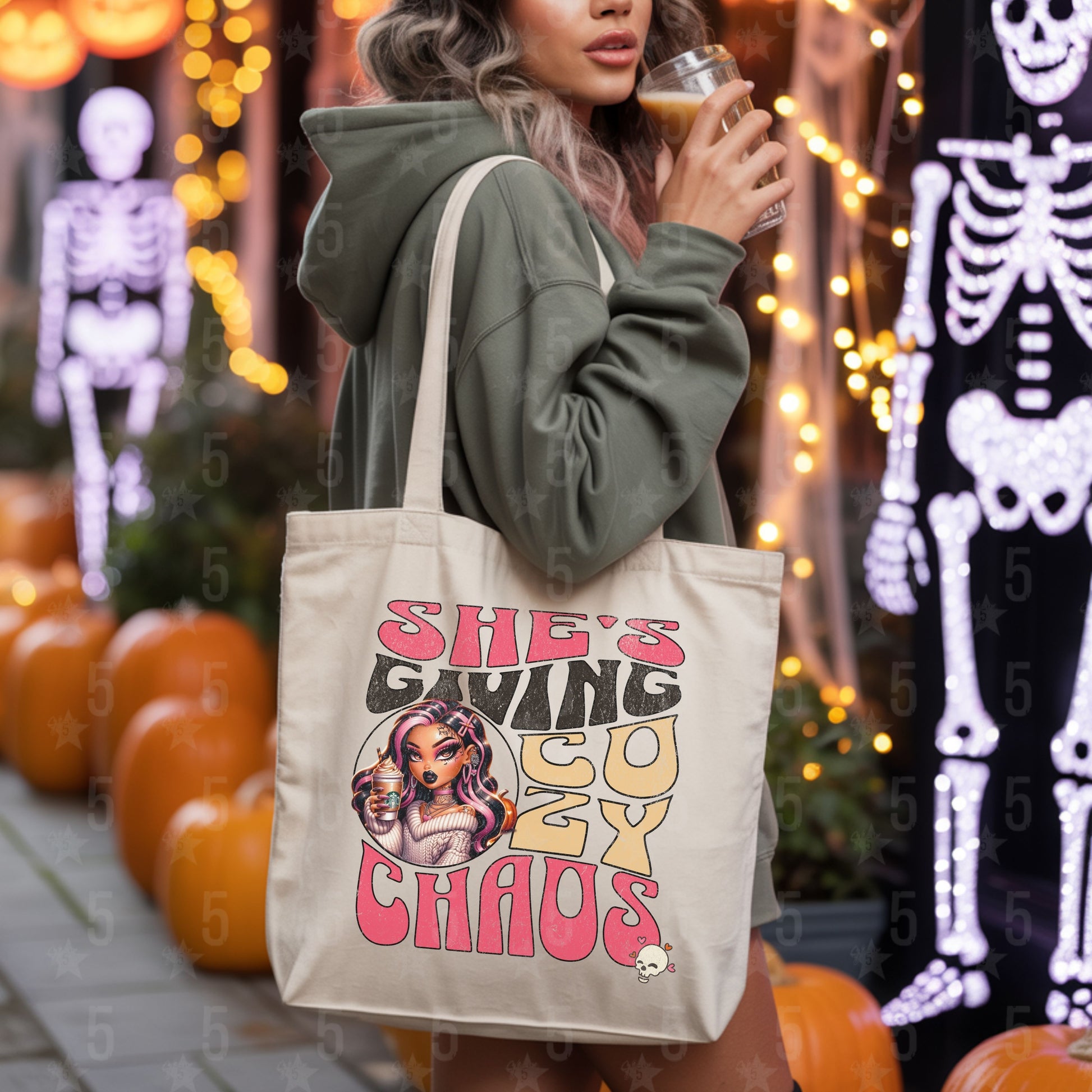 Person holding a tote bag with a graphic design and text, surrounded by Halloween decorations.