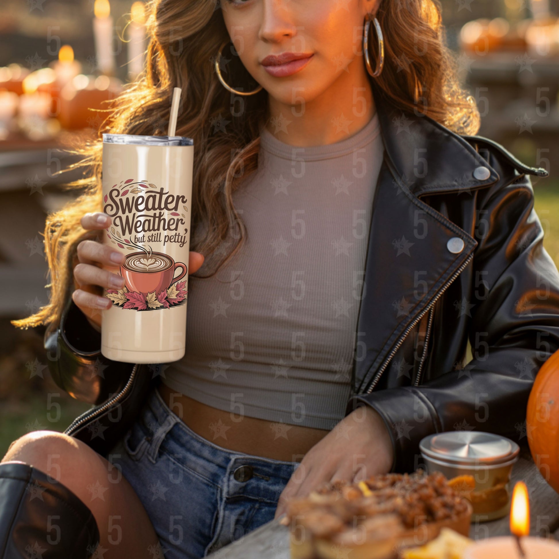 Woman holding a tumbler with a fall-themed design, sitting outdoors with pumpkins and food.