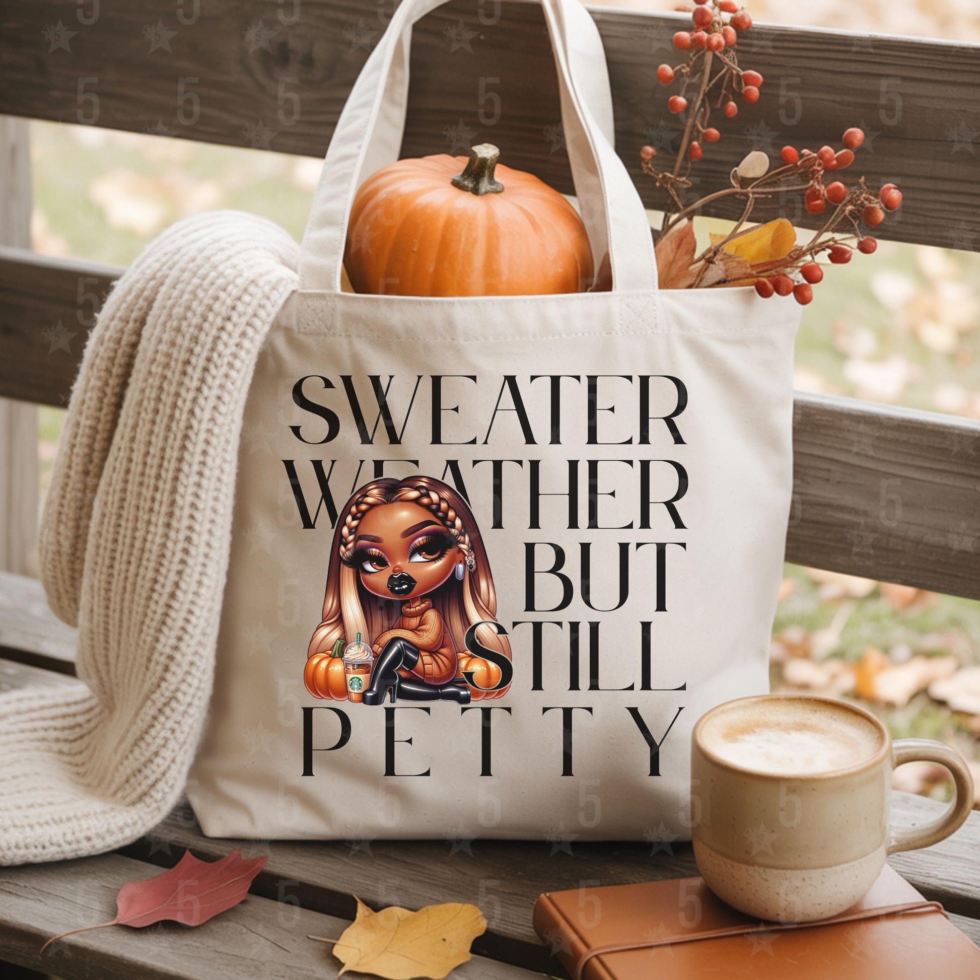 Tote bag with 'Sweater Weather But Still Petty' text and a cartoon character, placed on a wooden surface with pumpkins and a cup.