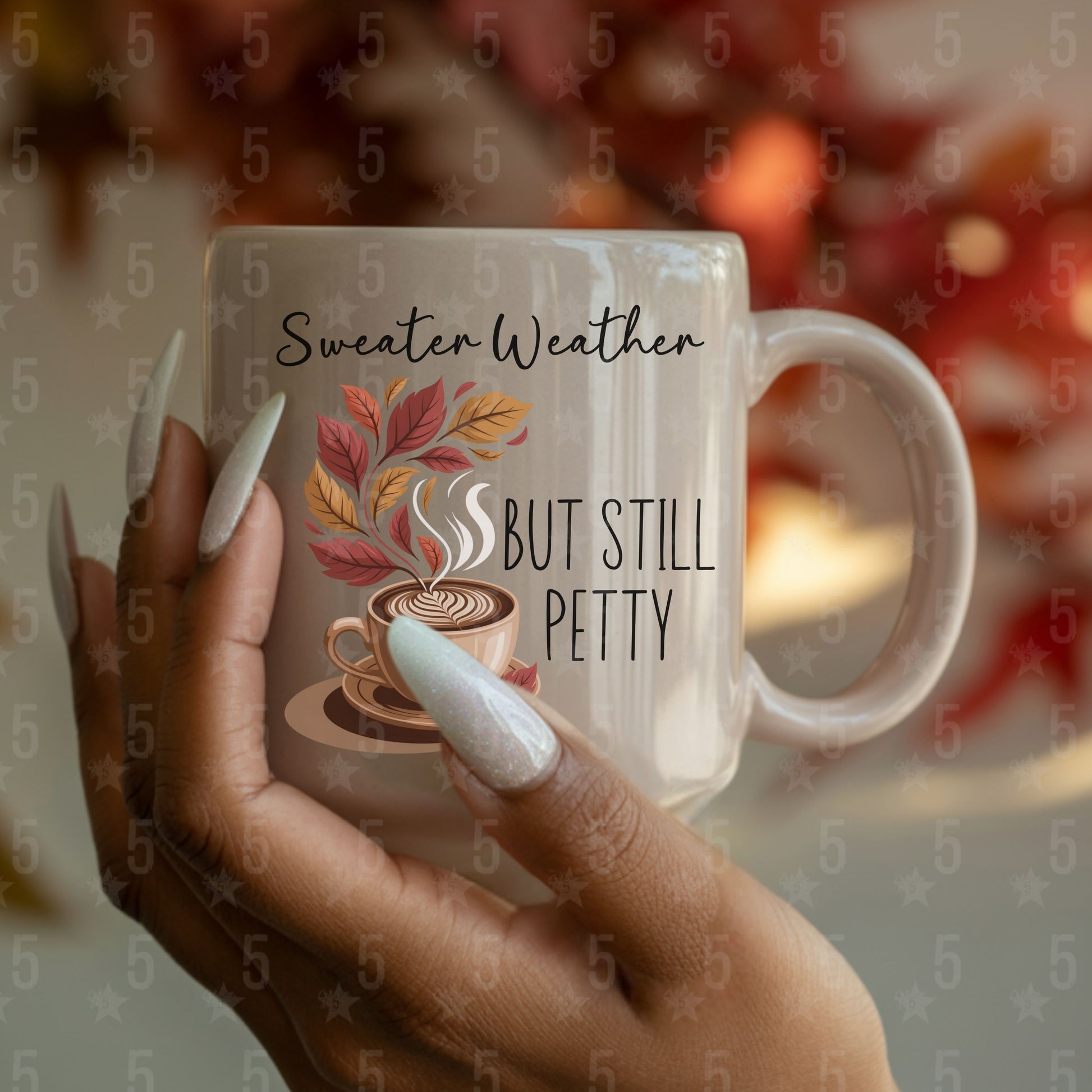 Mug with 'Sweater Weather, But Still Petty' text and autumn design held by a hand.