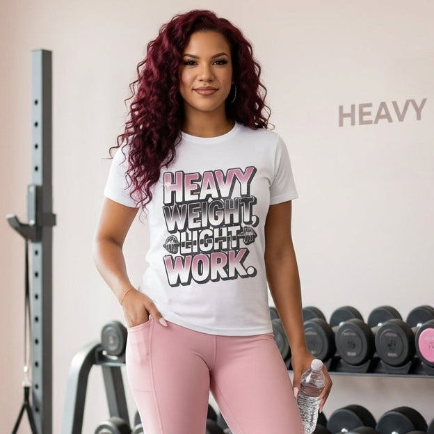 Woman in a gym wearing a 'Heavy Weight, Light Work' t-shirt and pink leggings.