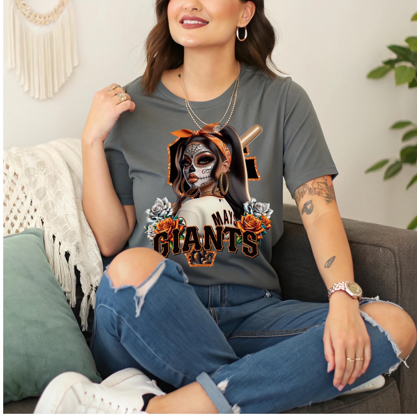 Woman wearing a t-shirt with a sf giants dia de los muertos design sitting on a couch.