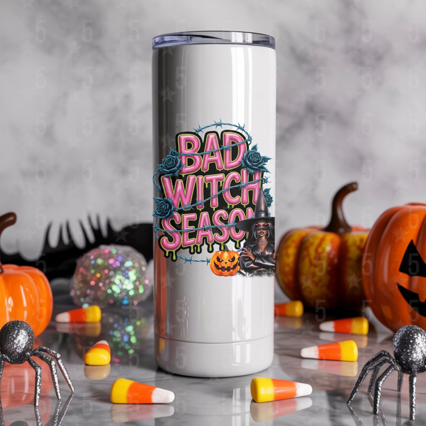 Tumbler with 'Bad Witch Season' design surrounded by Halloween decorations on a gray background