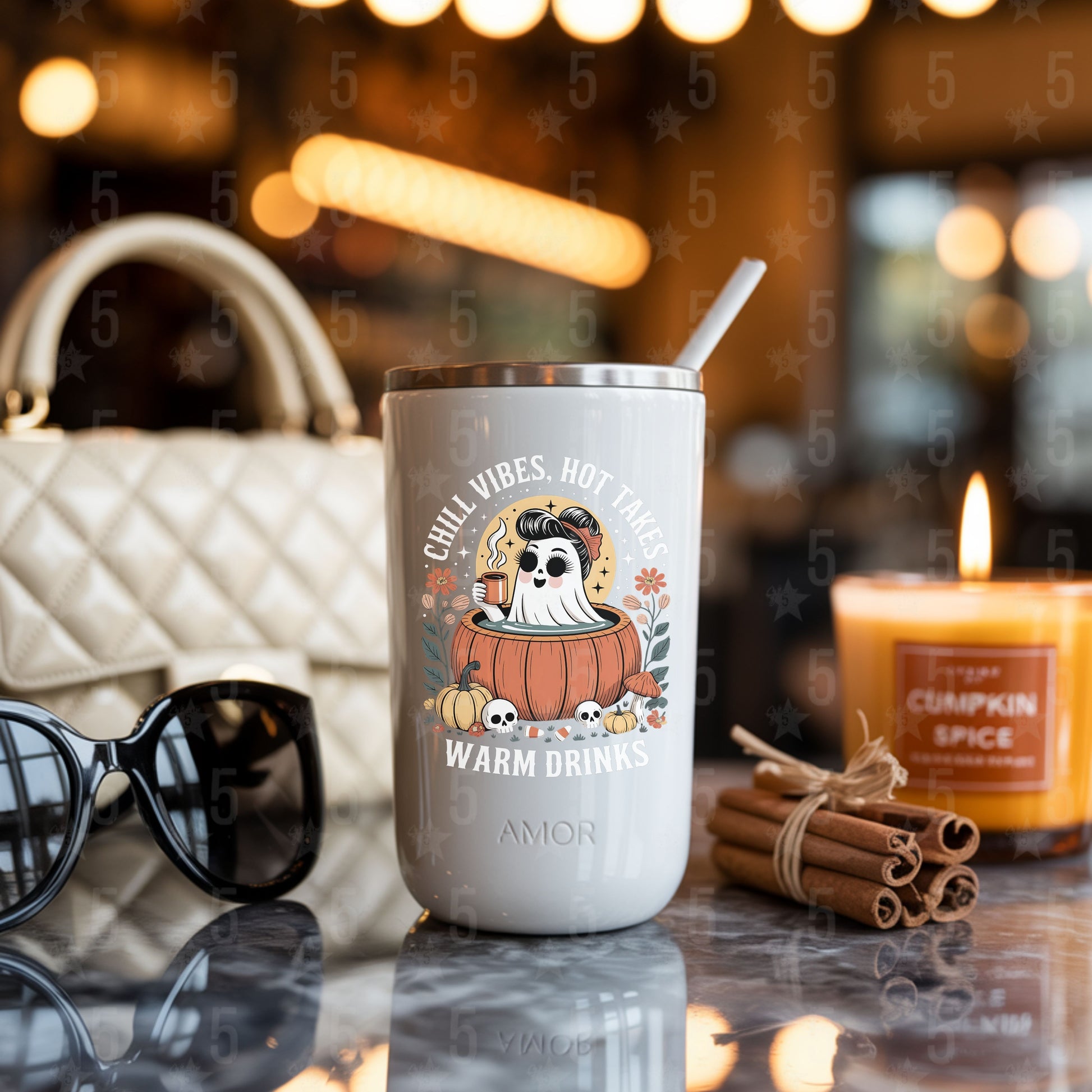 coffee tumbler surrounded by cinnamon sticks, candles, chanel bag and sunglasses