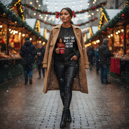 Woman walking through a festive market holding a coffee cup, wearing a long coat and black pants.