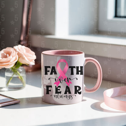 Mug with pink ribbon and 'Faith over Fear always' text on a desk with flowers and a phone.