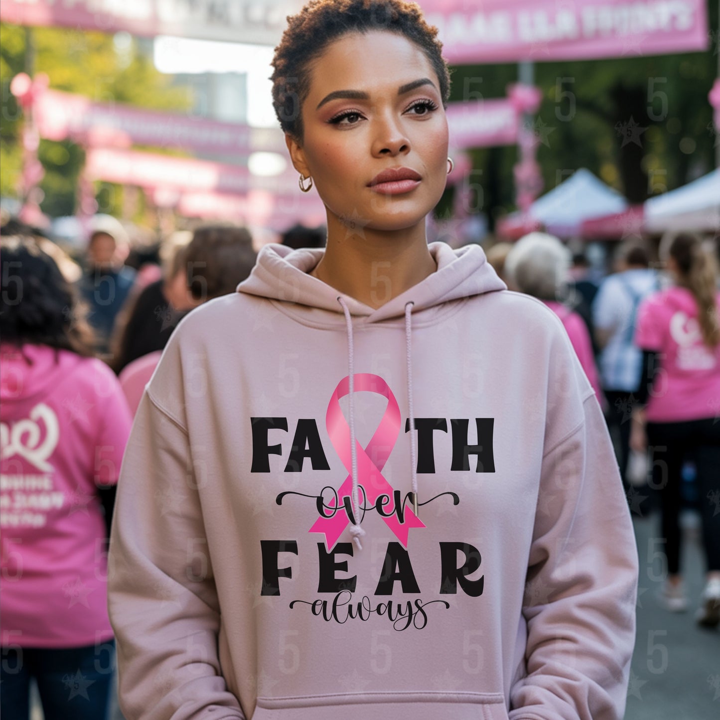 Woman wearing a pink hoodie with a breast cancer awareness message at an event.