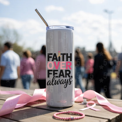 Tumbler with 'Faith Over Fear, always' text on a wooden table with pink ribbons and a blurred outdoor background.