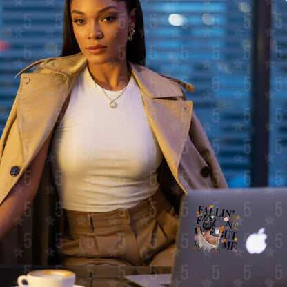 Woman in a beige trench coat sitting at a desk with a laptop and coffee cup, with a blurred background.
