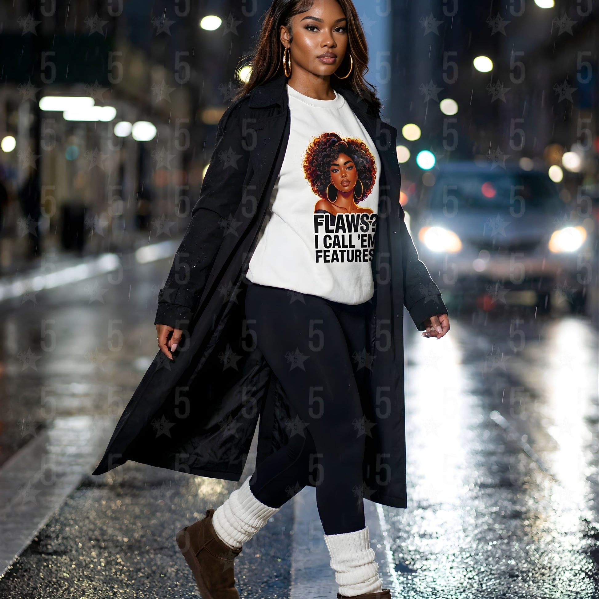 Woman walking on a city street at night wearing a long coat and a t-shirt with a graphic design.
