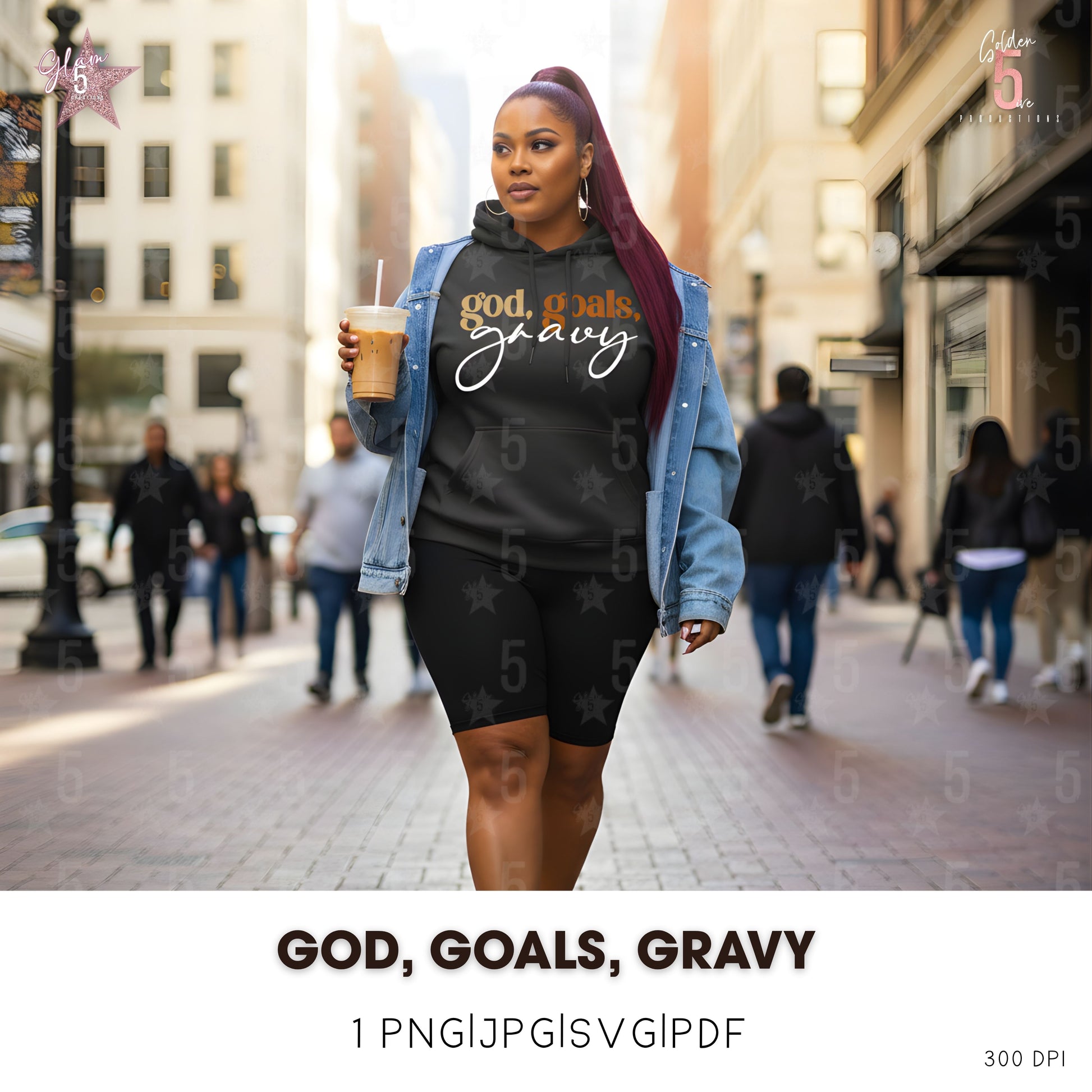 Woman walking on a city street wearing a black sweatshirt with 'god, goals, gravy' text.