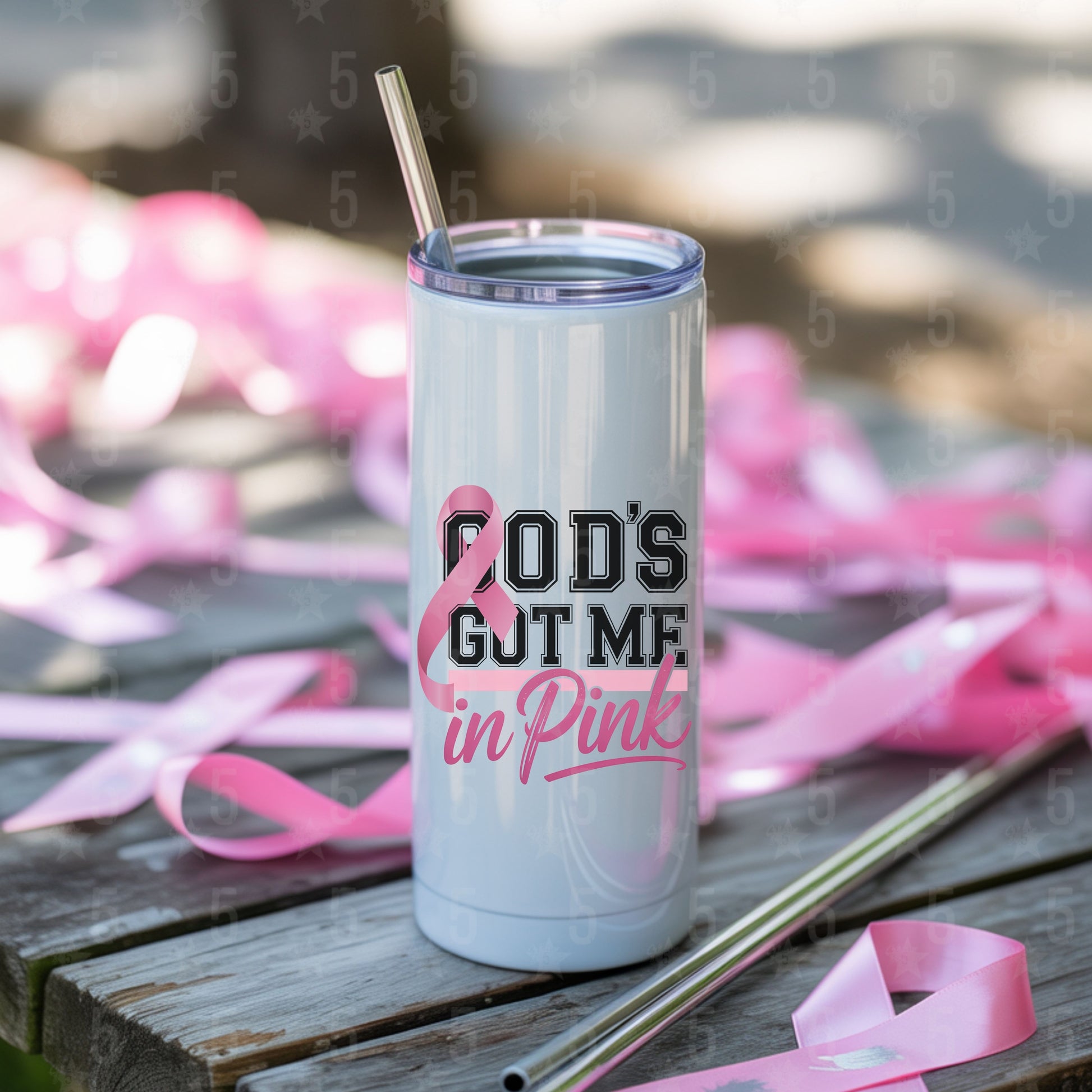 Tumbler with 'God's Got Me in Pink' text and breast cancer awareness ribbons on a wooden surface.