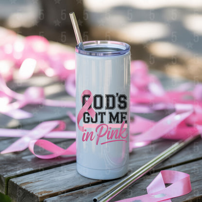Tumbler with 'God's Got Me in Pink' text and breast cancer awareness ribbons on a wooden surface.