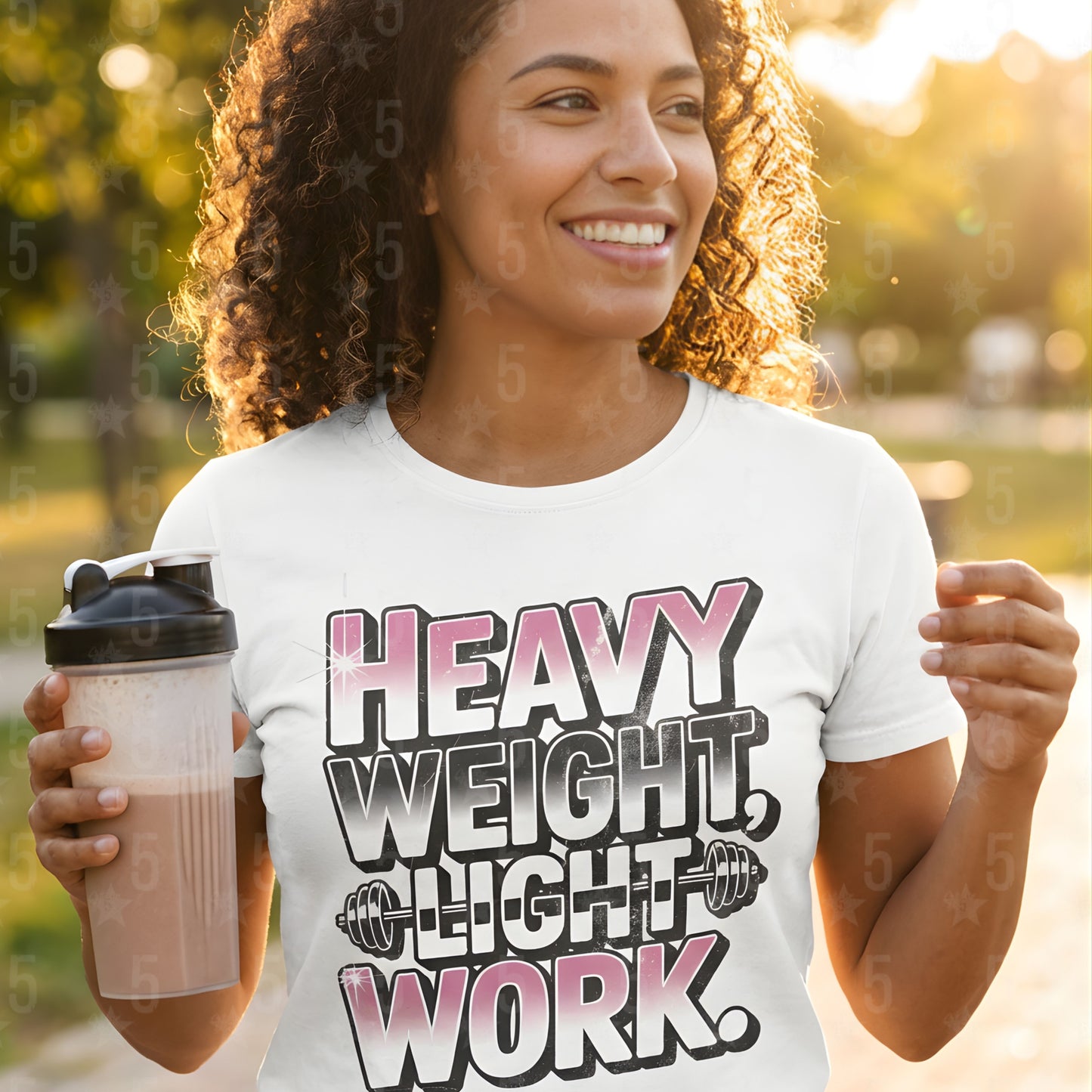 Woman wearing a t-shirt with 'Heavy Weight, Light Work' text, holding a shaker bottle outdoors.