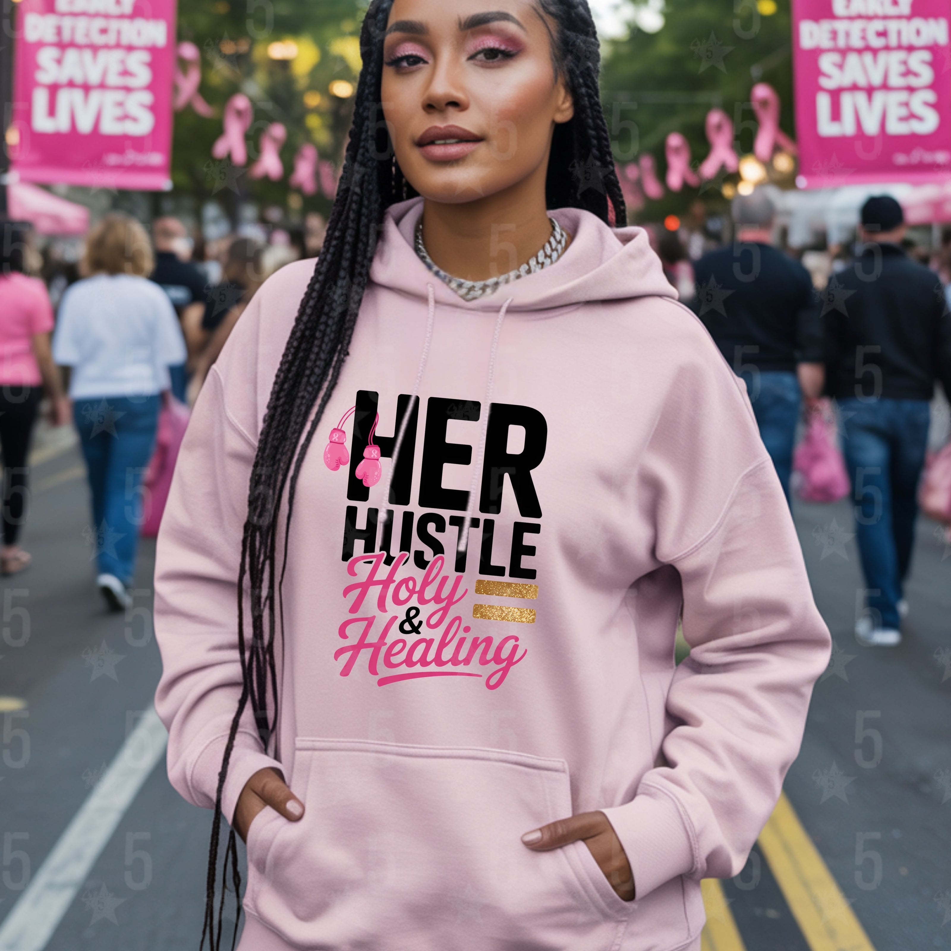 Woman wearing a pink hoodie with text at an event with 'HER HUSTLE Holy & Healing' message.