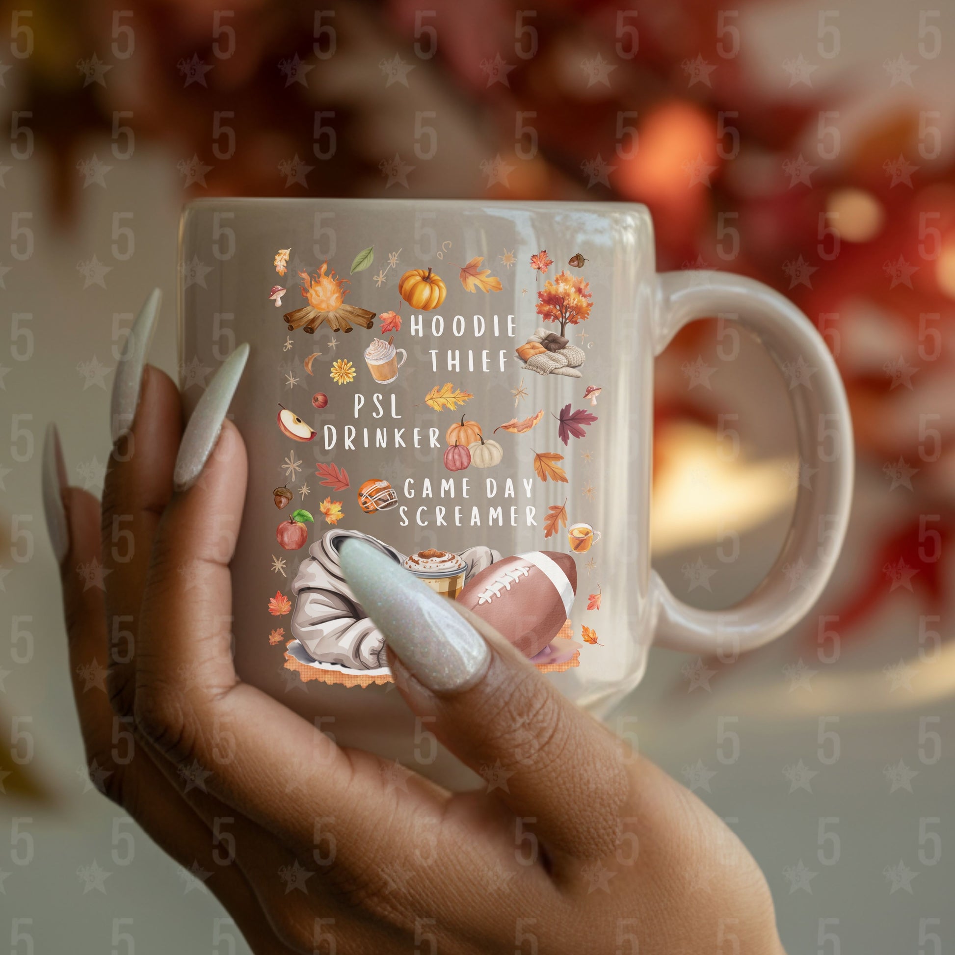 Mug with autumn-themed text and graphics held by a hand with painted nails.