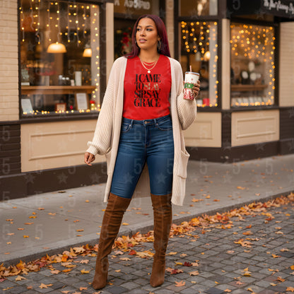 Woman in red shirt and blue jeans standing on a sidewalk with a store in the background