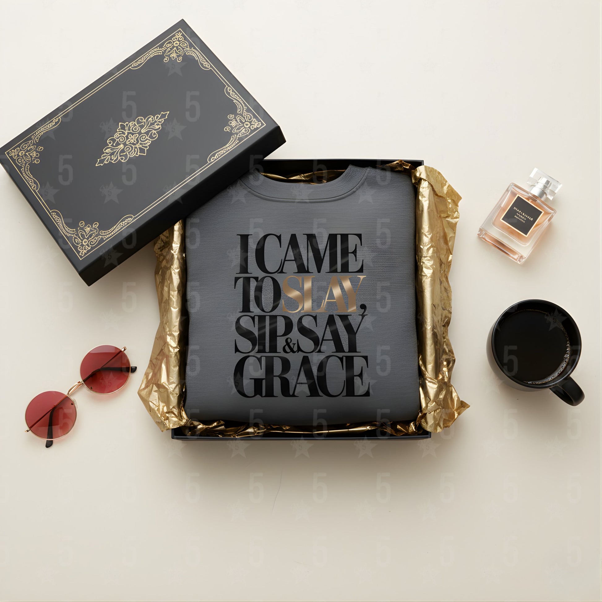 Black t-shirt with text, sunglasses, mug, and perfume bottle on a light surface