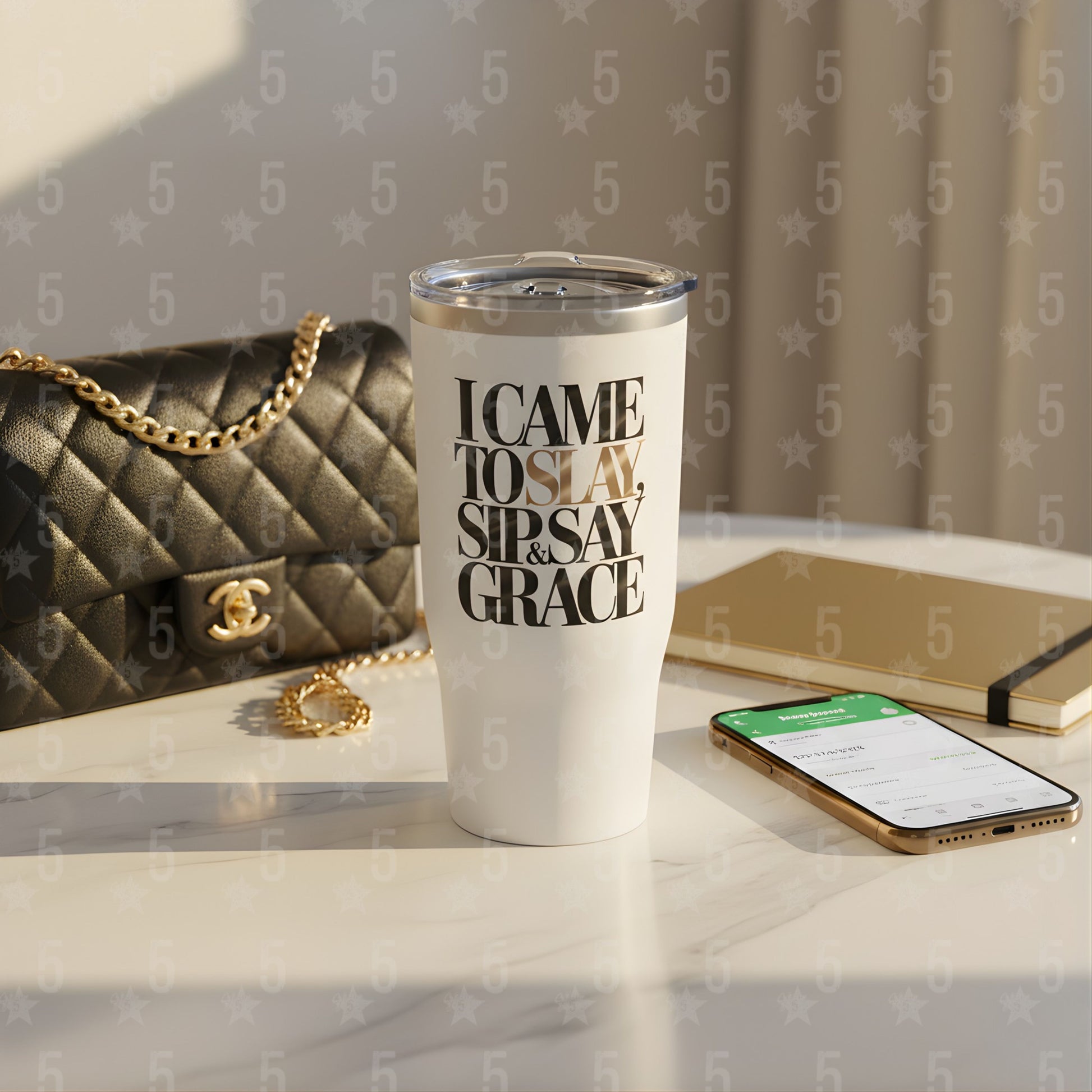 White tumbler with text on a surface with a handbag and phone in the background