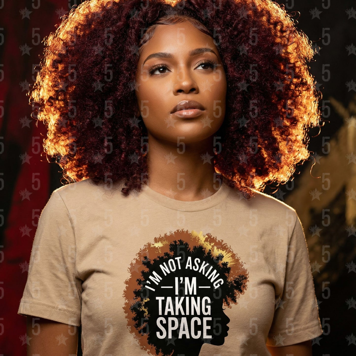 Woman wearing a beige t-shirt with a graphic and text, standing against a dark background.