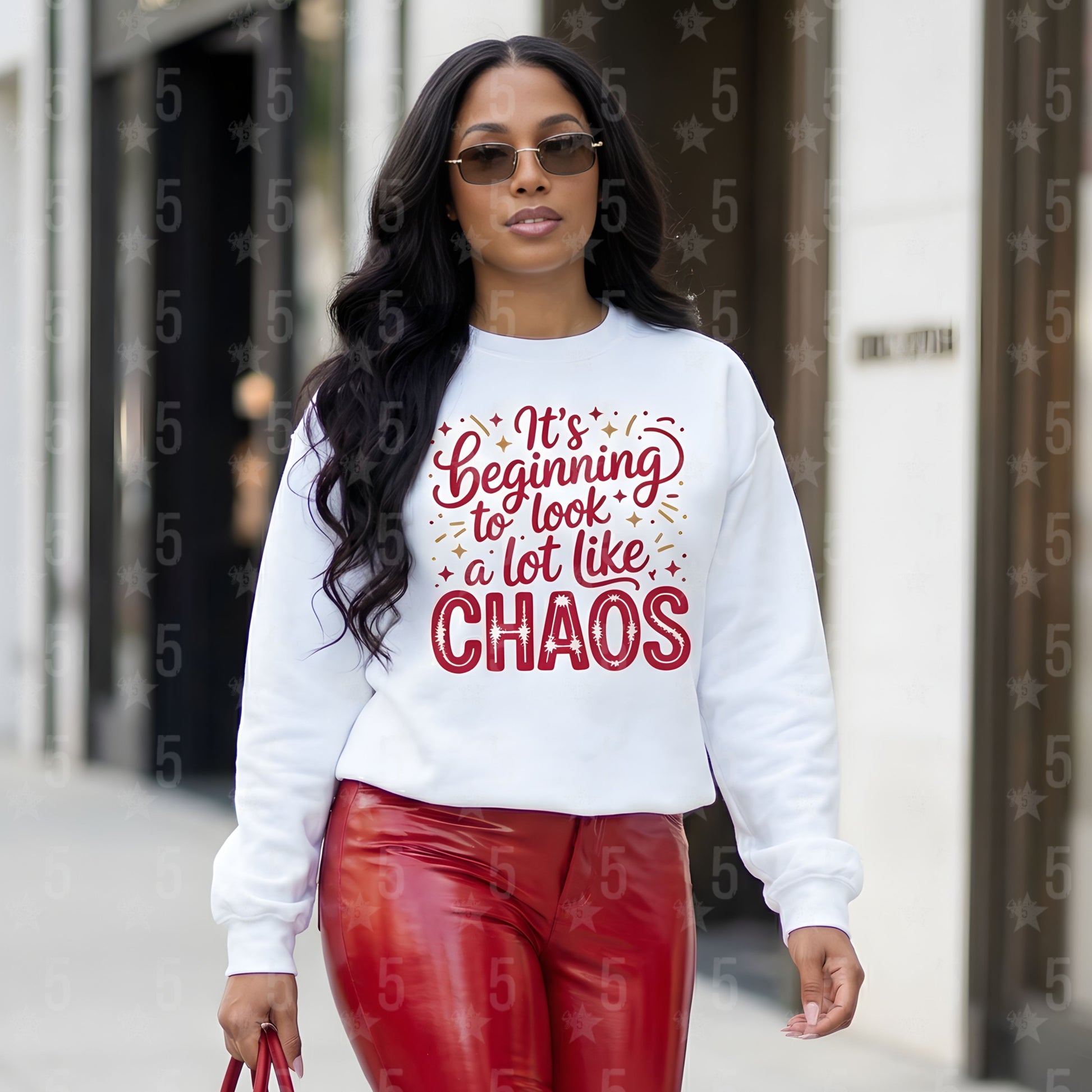 Woman wearing a white sweatshirt with red text and red pants walking outdoors.
