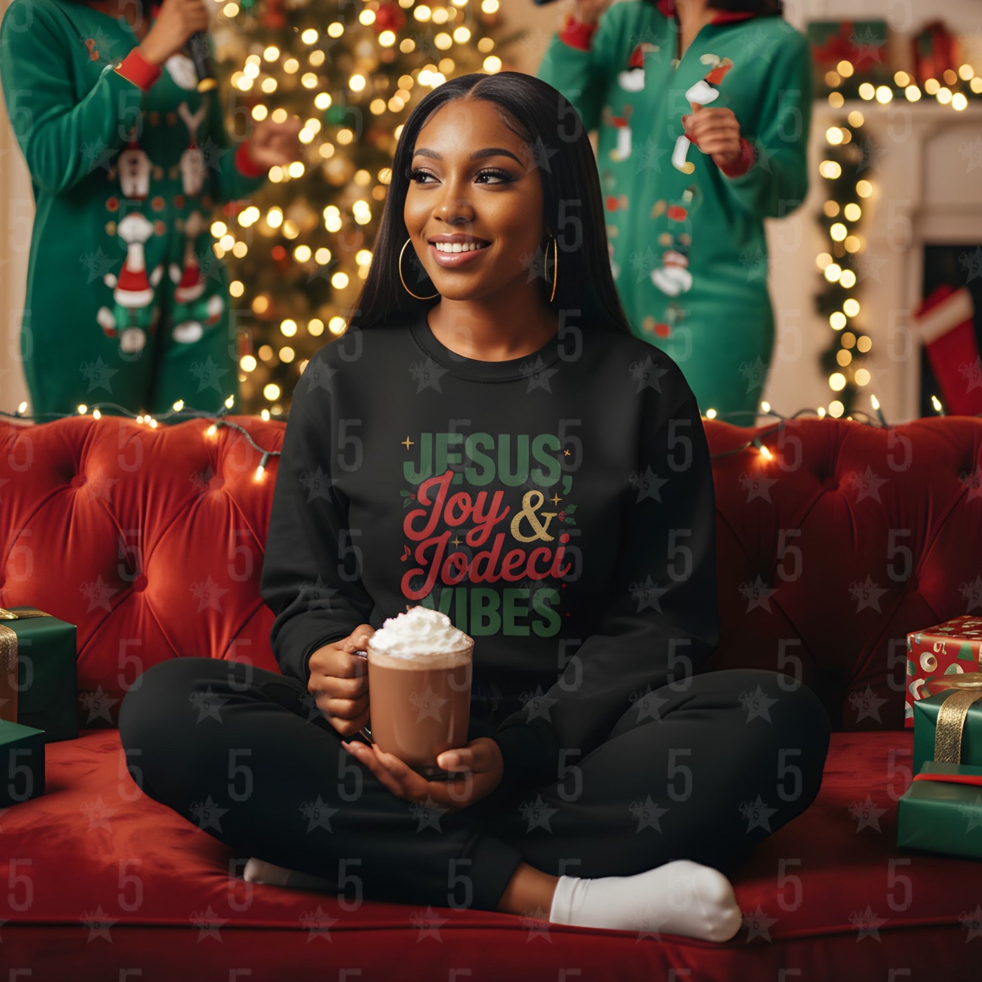 Woman wearing a black sweatshirt with Christmas-themed text, sitting on a red couch holding a mug, with festive decorations in the background.
