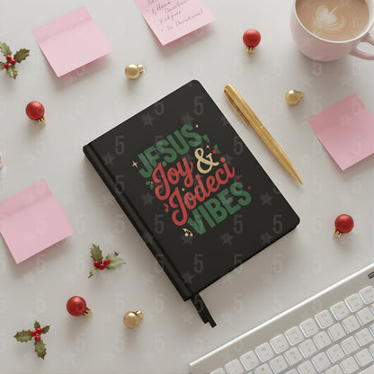 Black notebook with colorful text on a desk with Christmas decorations and a cup of coffee.