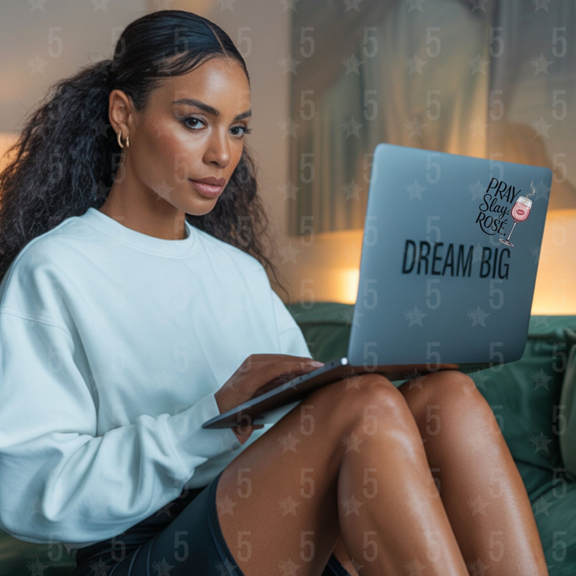 Woman sitting on a couch using a laptop with 'Dream Big' sticker.