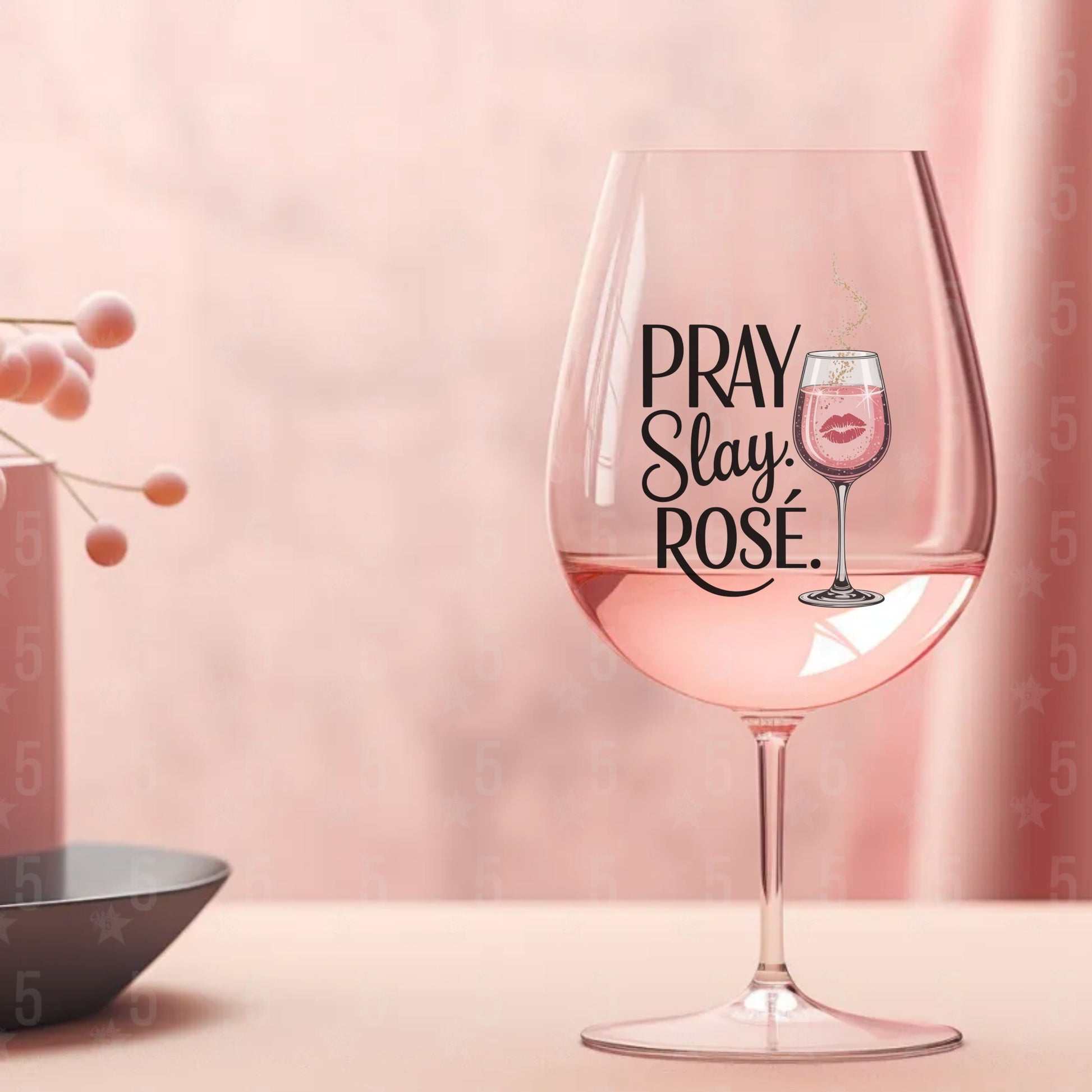 Wine glass with 'PRAY SLAY ROSE' text on a pink background