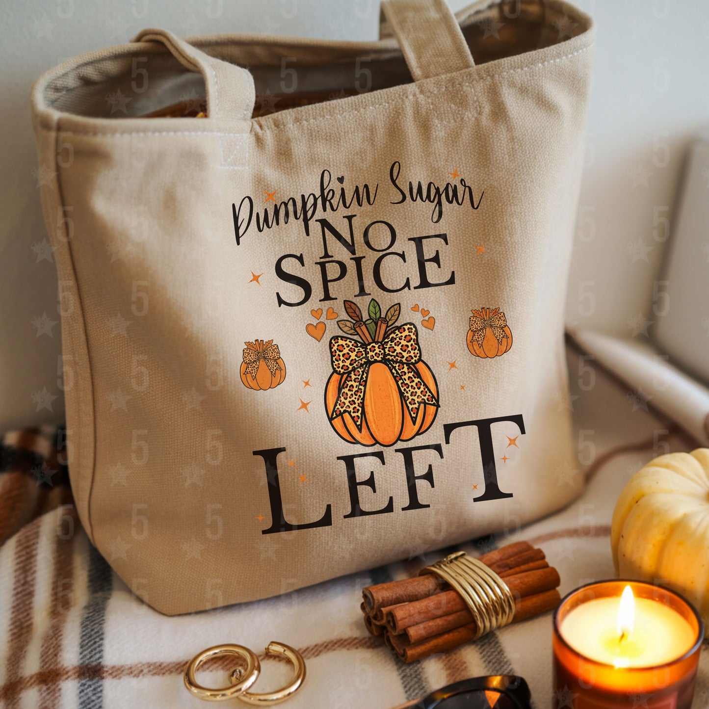 Beige tote bag with pumpkin spice text on a cozy setting with candles and pumpkins.