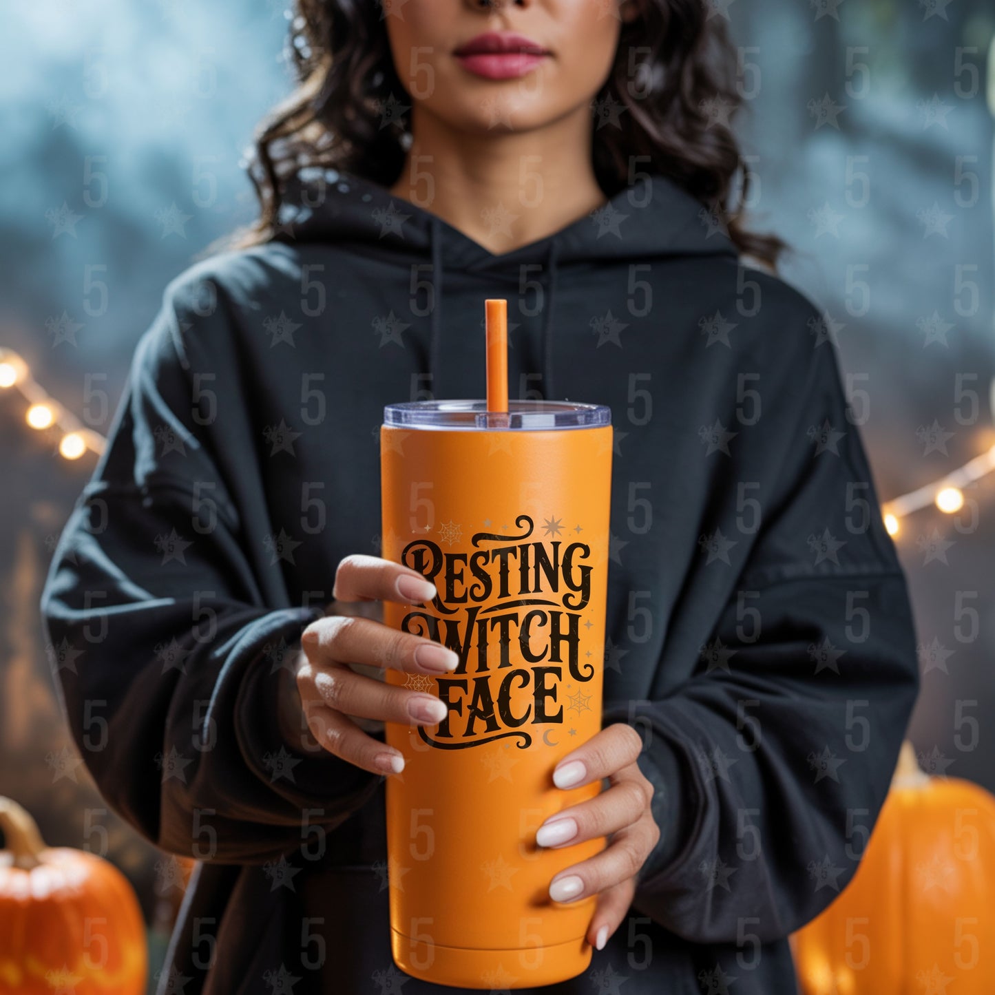 Person wearing a black hoodie holding an orange tumbler with 'Besting Witch Face' text, surrounded by pumpkins and string lights.