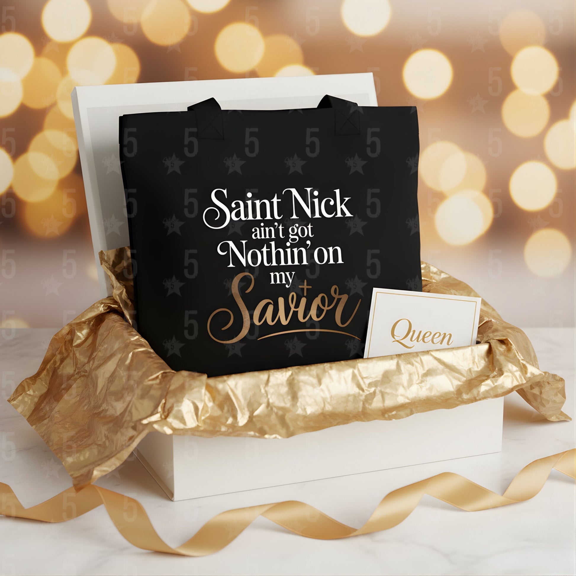 Black tote bag with text on a white box with gold ribbon, blurred lights in the background