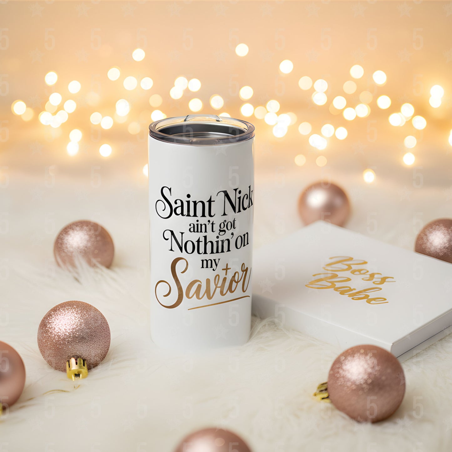 Tumbler with Christmas-themed text and decorations on a soft surface with lights in the background