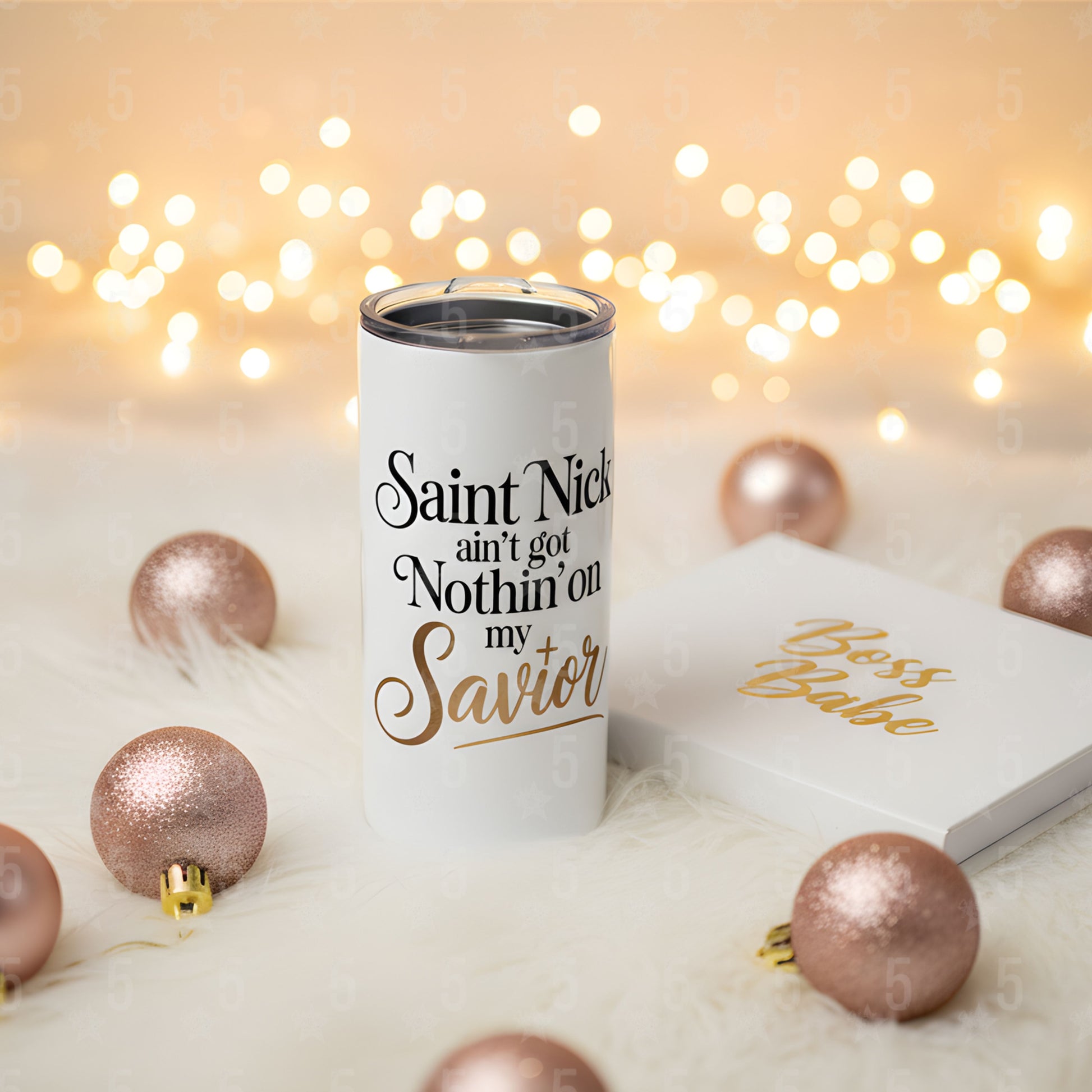 Tumbler with Christmas-themed text and decorations on a soft surface with lights in the background
