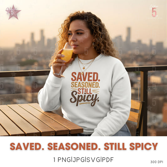 Woman in a 'Saved. Seasoned. Still Spicy' sweatshirt drinking orange juice on a rooftop with a cityscape in the background.