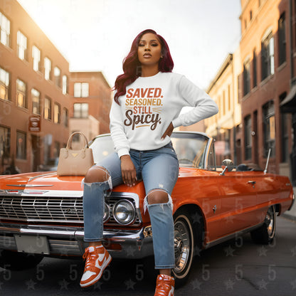 Woman sitting on a classic red car wearing a white sweatshirt with text, in an urban setting.