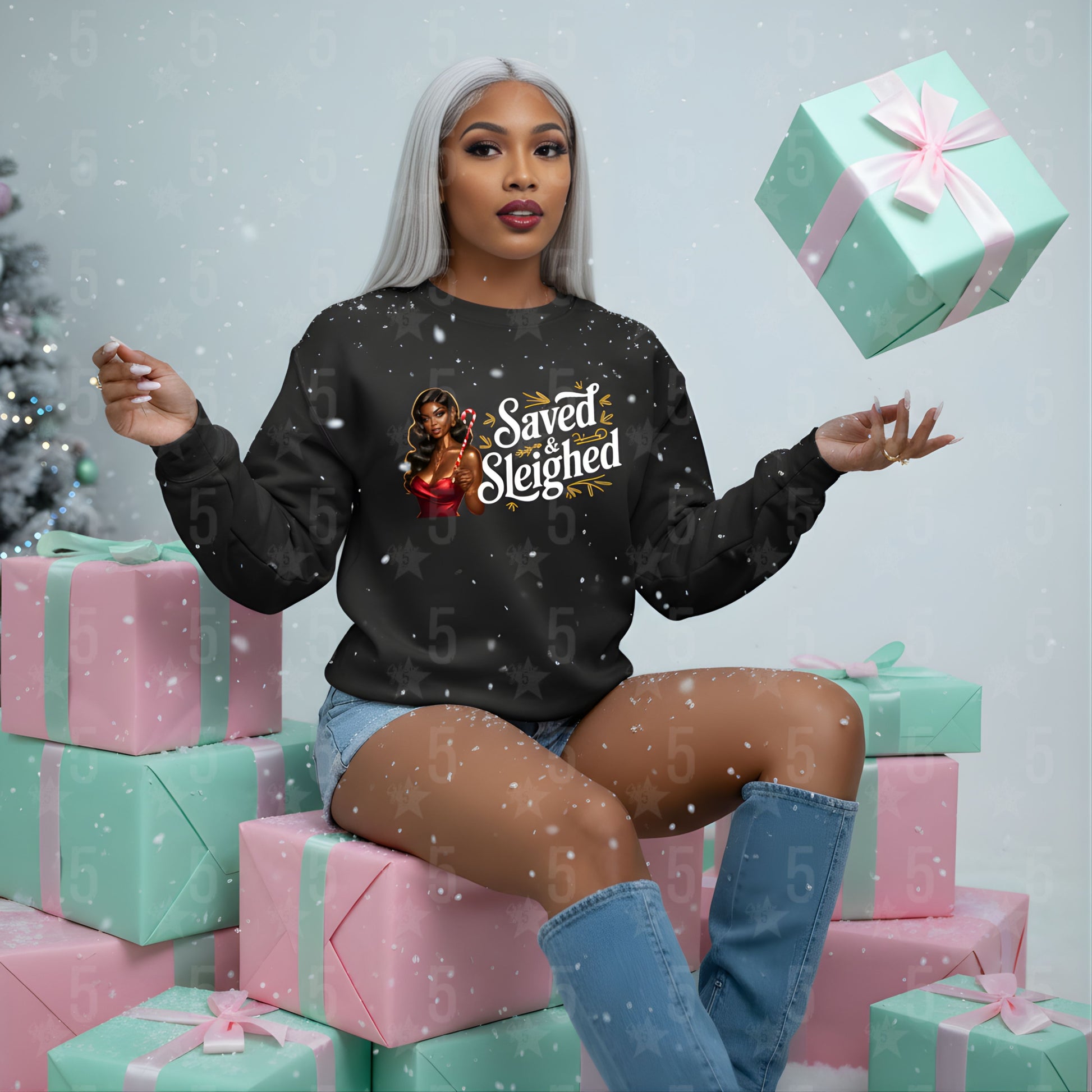 Woman wearing a black sweatshirt with text and graphics, sitting on presents with a festive background.