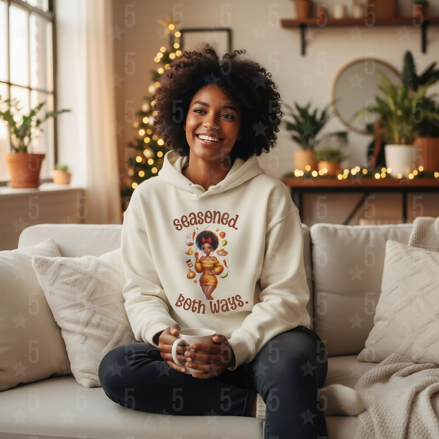 Woman wearing a hoodie with a graphic design sitting on a couch in a cozy living room.