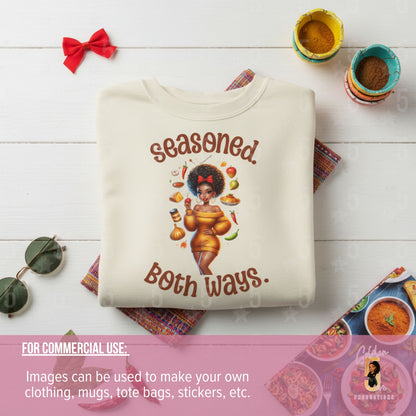 Folded sweatshirt with 'Seasoned Both Ways' graphic on a wooden surface with decorative items.