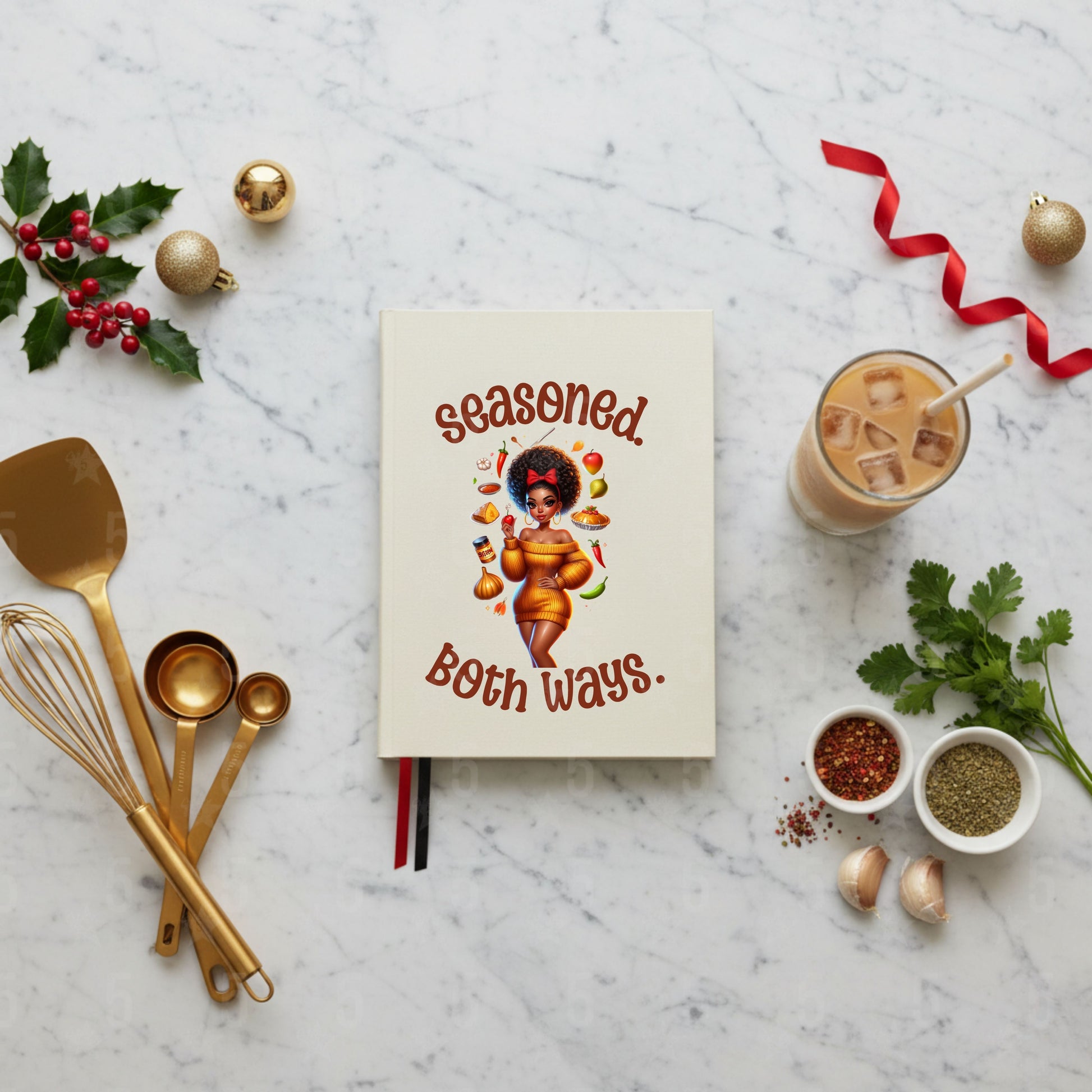 Notebook titled 'Seasoned Both Ways' with kitchen utensils and ingredients on a marble surface